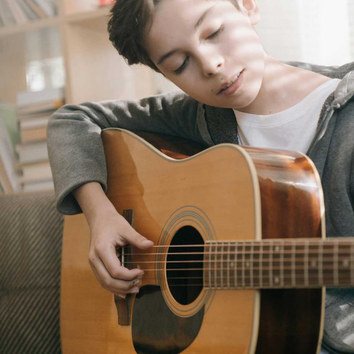 A young boy playing the acoustic guitar fingerstyle