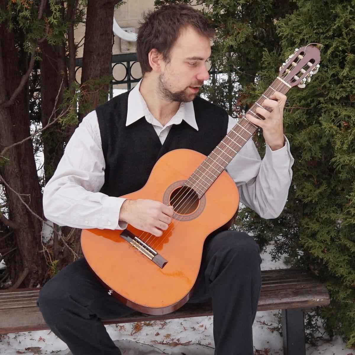 Brett sitting on a park bench outside in the winter playing a classical guitar and showing off his incredible finger independence exercises for guitar players