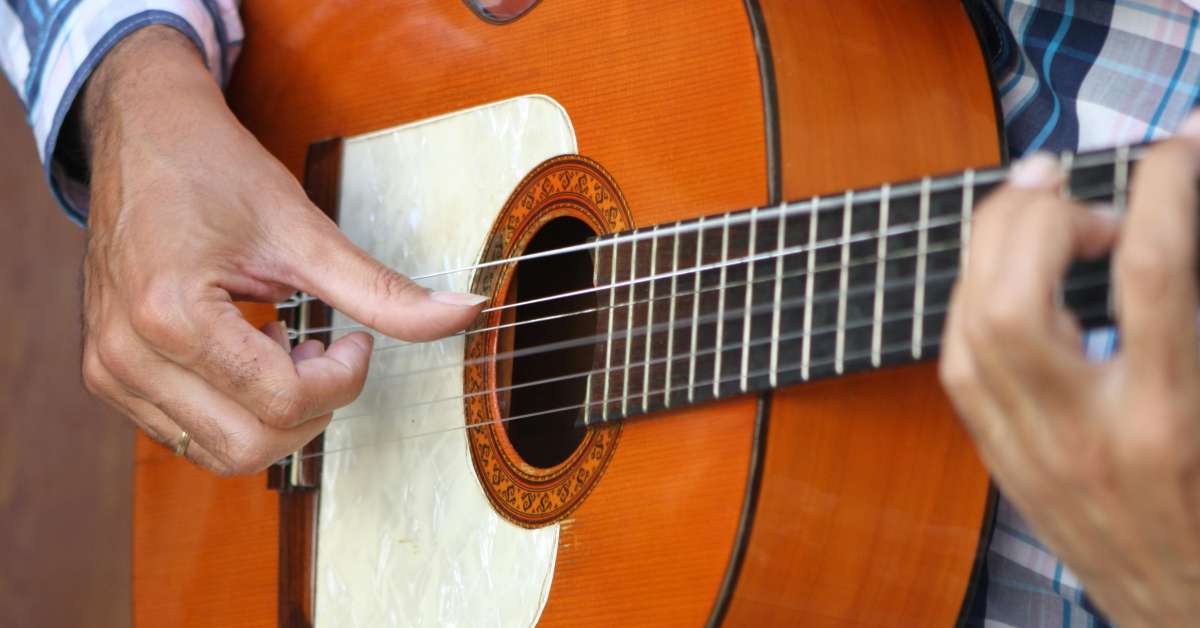 An image of the thumb plucking the fifth string of the classical guitar