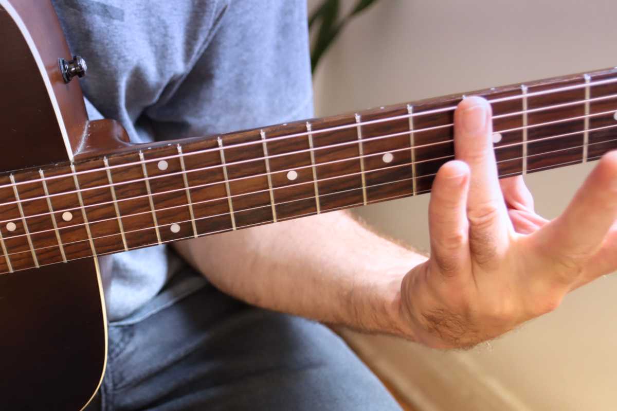 An image of the finger producing a Guitar Harmonic at the fifth Fret