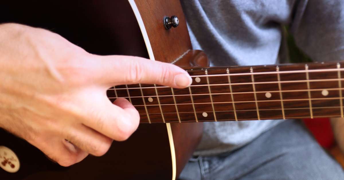 An image of the technique to produce a harp harmonic on the guitar