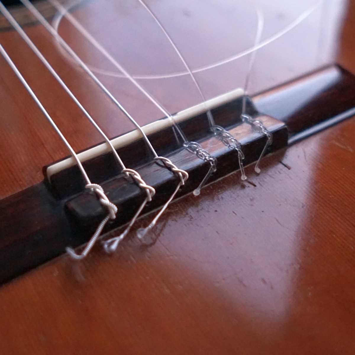 An image of the bridge of the classical guitar showing tie-end guitar strings